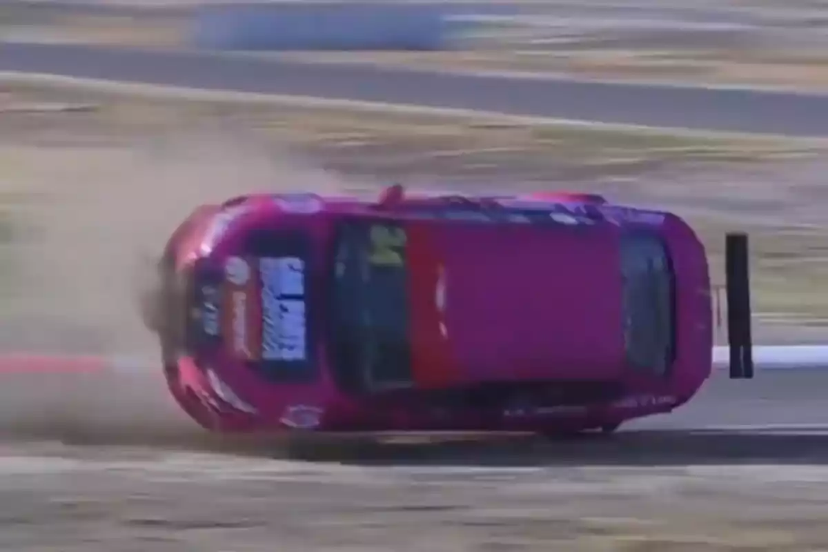Auto deportivo color rosa volcándose en una pista de carreras mientras levanta polvo