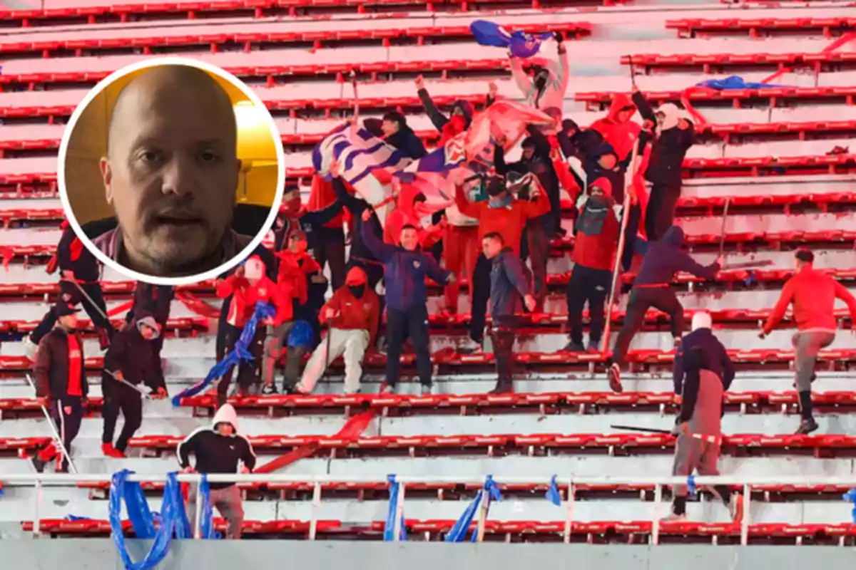 A group of people wearing red and blue clothing are involved in a fight in the stands of a stadium, while in the upper left corner the face of a bald man appears inside a circle.