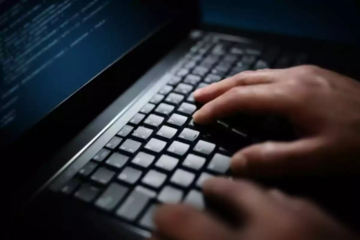 Manos escribiendo en el teclado de una computadora portátil con la pantalla mostrando líneas de código Manos escribiendo en el teclado de una computadora portátil con la pantalla mostrando líneas de código