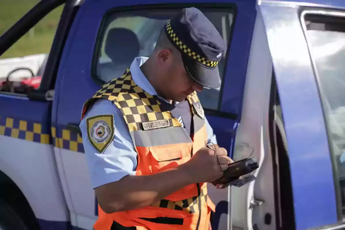 Traffic officer in uniform and cap writing a ticket next to a blue patrol car Traffic officer in uniform and cap writing a ticket next to a blue patrol car