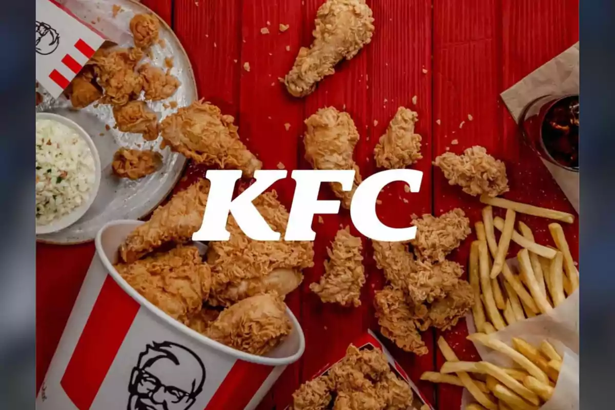 Pollo frito de KFC acompañado de papas fritas, ensalada y refresco sobre una mesa roja