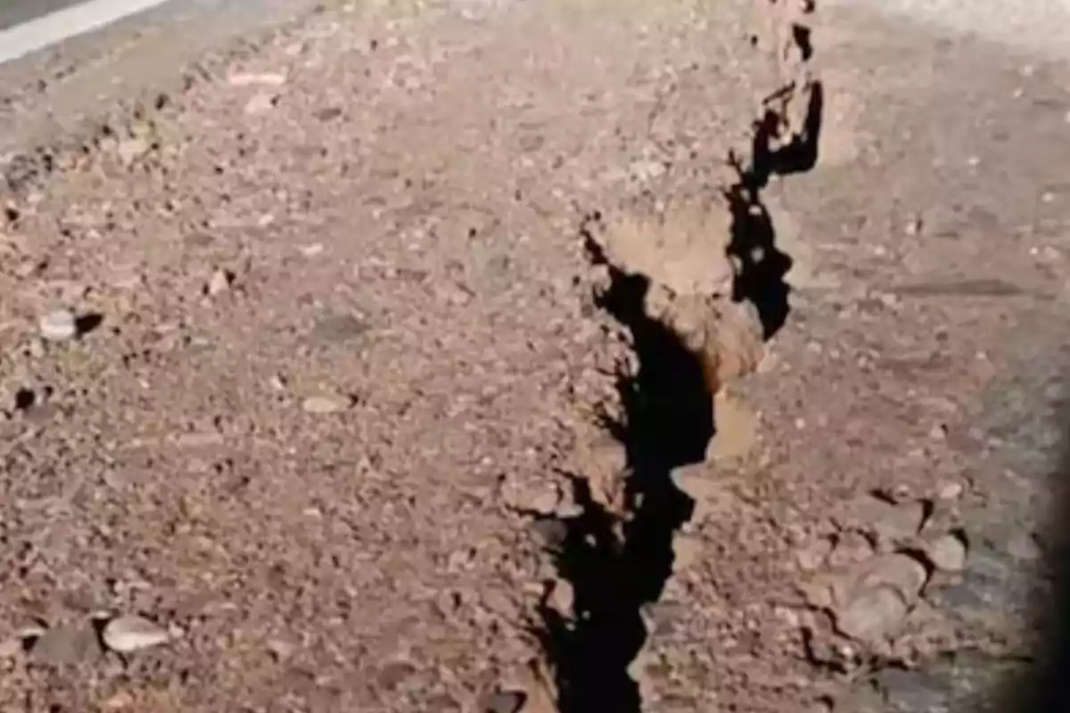 Deep crack in the ground of a dirt road caused by an earthquake Deep crack in the ground of a dirt road caused by an earthquake