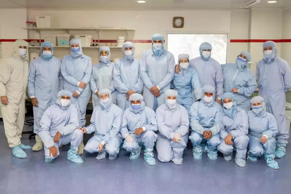 Group of people wearing blue protective suits and masks posing in a clean laboratory Group of people wearing blue protective suits and masks posing in a clean laboratory