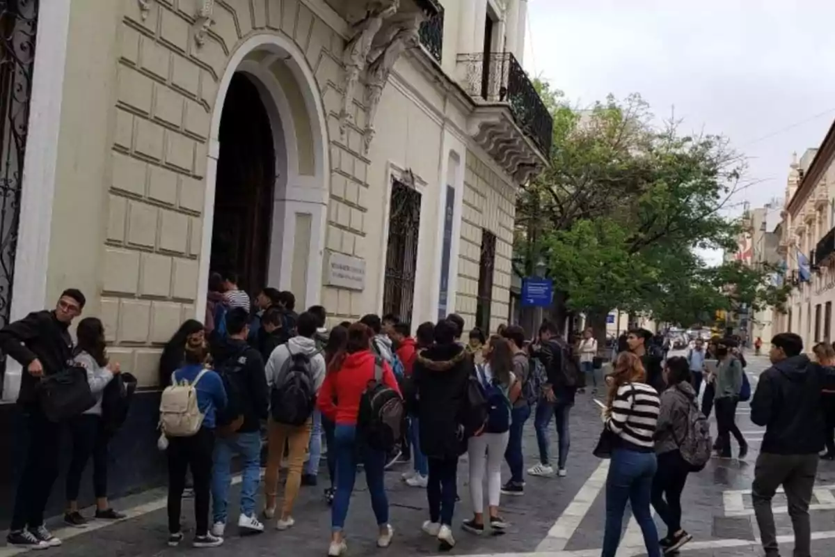 A group of students with backpacks is waiting to enter an old building on a pedestrian street. A group of students with backpacks is waiting to enter an old building on a pedestrian street.