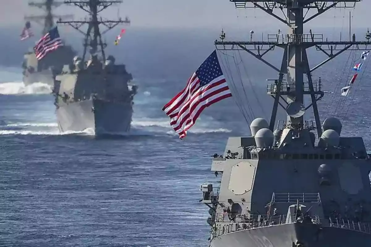 Tres buques de guerra de la marina de Estados Unidos navegan en formación sobre el mar con banderas estadounidenses ondeando Tres buques de guerra de la marina de Estados Unidos navegan en formación sobre el mar con banderas estadounidenses ondeando