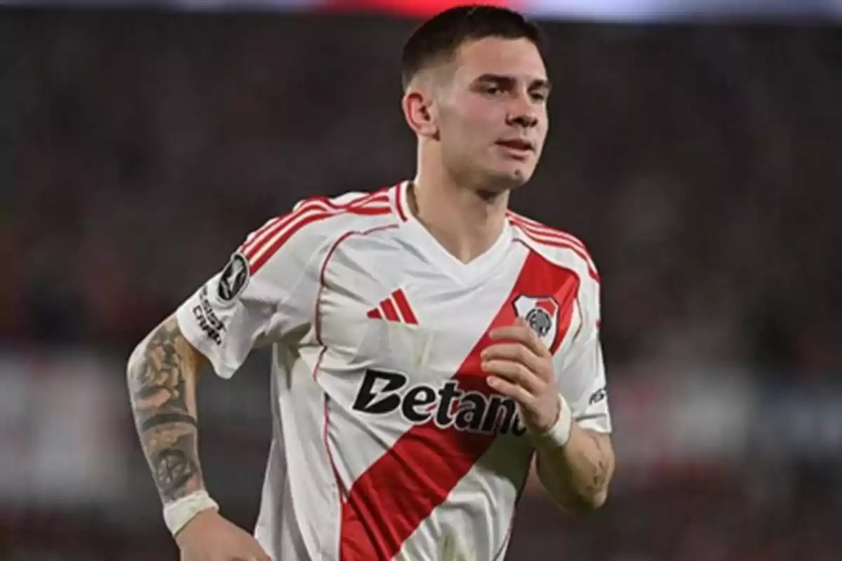 Soccer player wearing River Plate’s white uniform with a red sash running on the field during a match