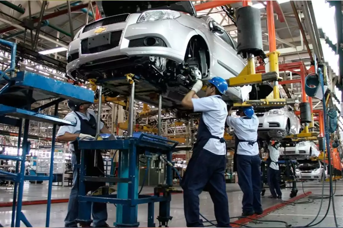 Trabajadores ensamblando automóviles en una línea de producción dentro de una fábrica industrial