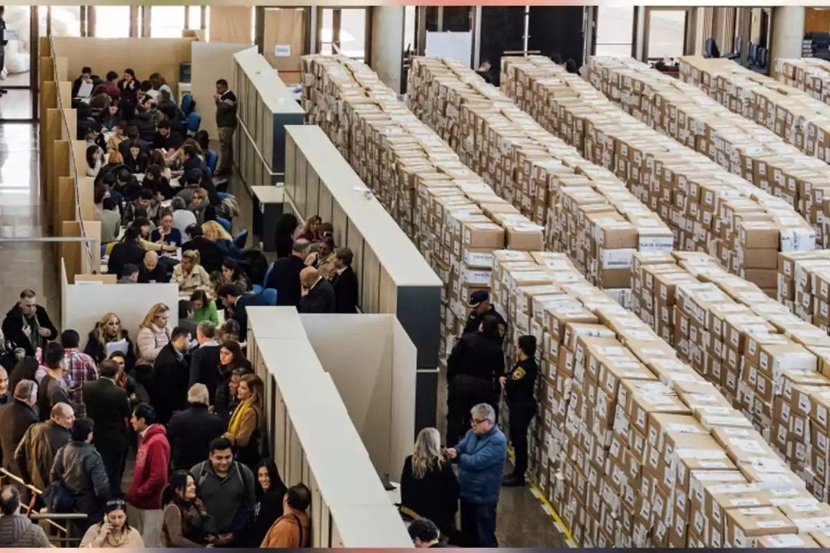 People gathered in a facility with many stacked boxes and staff working at tables