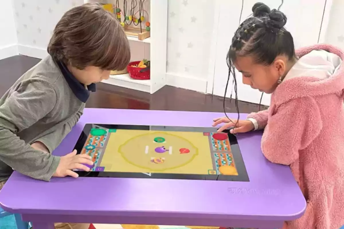 Dos niños juegan en una mesa interactiva táctil de color morado en un ambiente infantil Dos niños juegan en una mesa interactiva táctil de color morado en un ambiente infantil