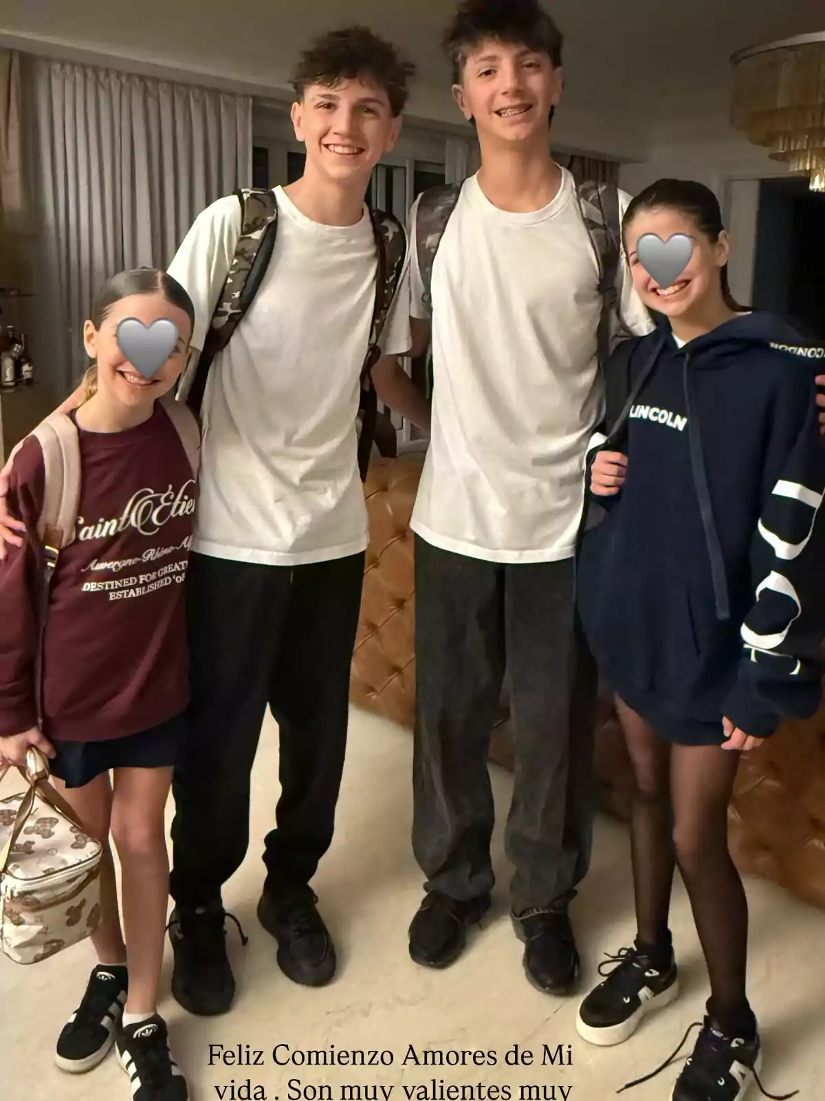Four smiling young people pose together in a room; two of them are wearing backpacks, and two girls have their faces covered with a gray heart. Four smiling young people pose together in a room; two of them are wearing backpacks, and two girls have their faces covered with a gray heart.