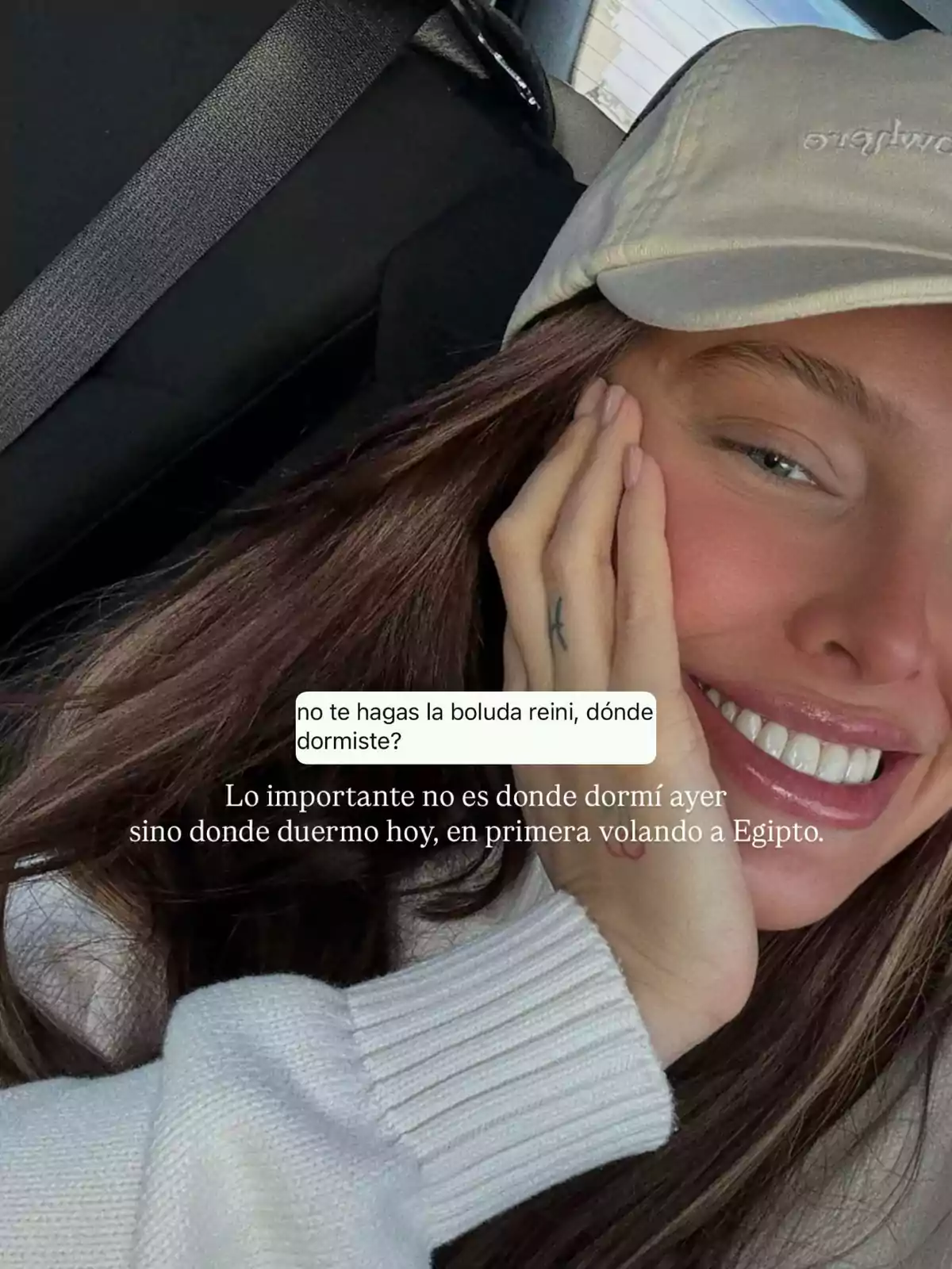 Selfie de una mujer sonriendo con gorra beige y suéter blanco, viajando en auto, con un texto sobre dormir en primera clase rumbo a Egipto. Selfie de una mujer sonriendo con gorra beige y suéter blanco, viajando en auto, con un texto sobre dormir en primera clase rumbo a Egipto.