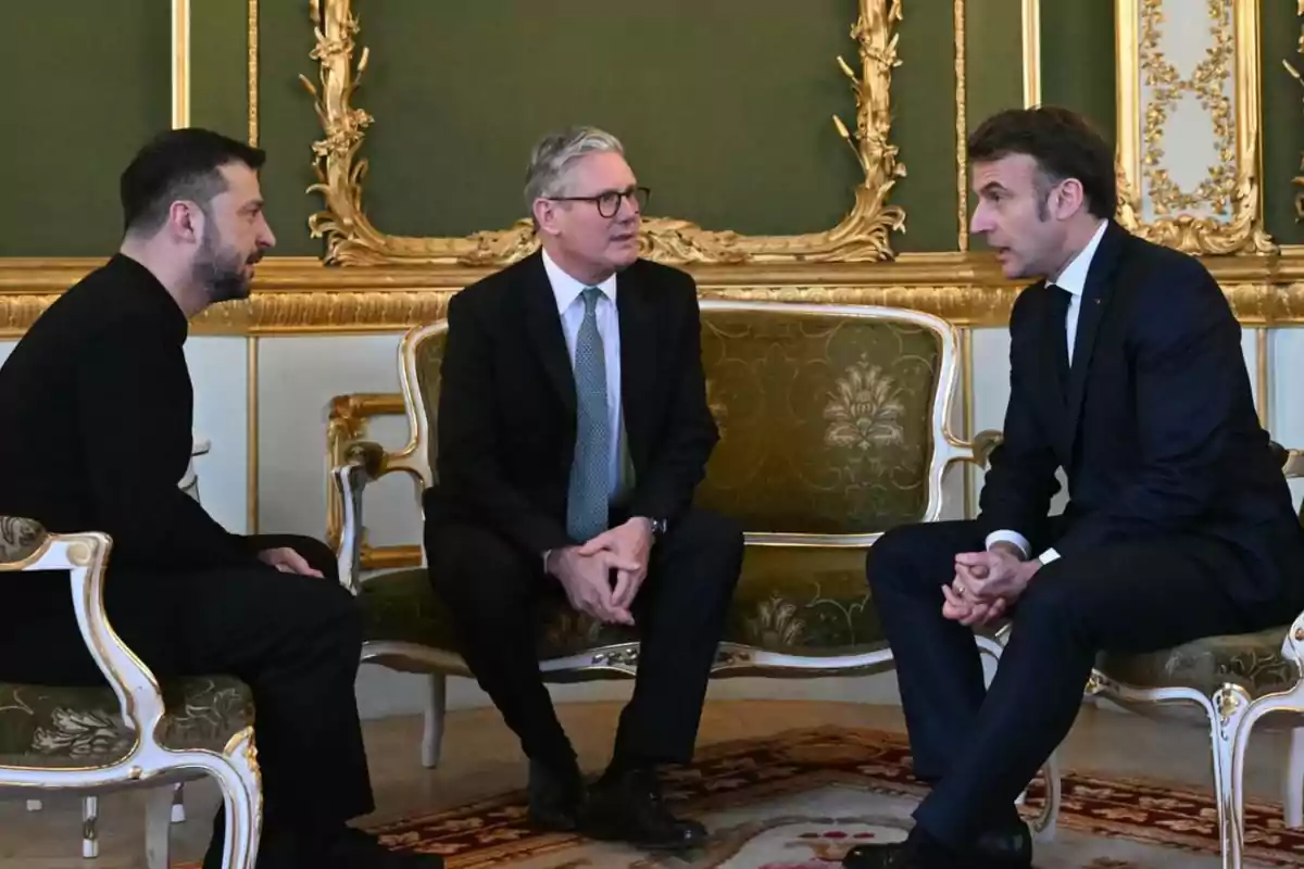 Tres hombres vestidos de traje conversan sentados en una sala elegante con muebles y decoración dorada
