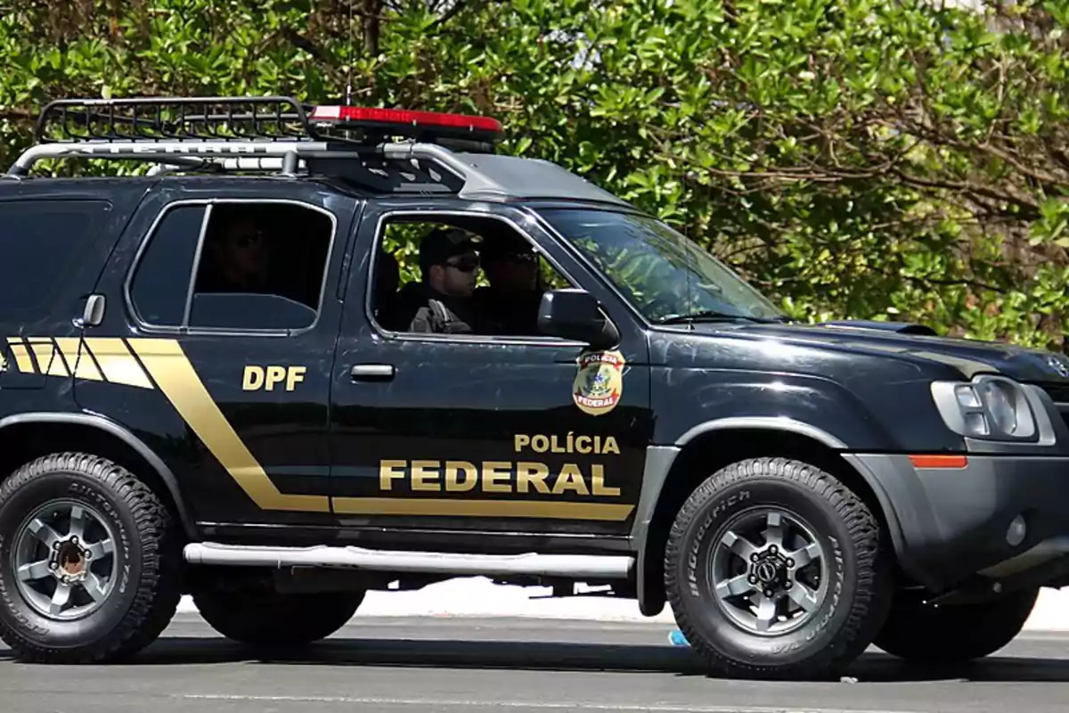 Black federal police pickup truck with two officers inside parked next to a vegetated area Black federal police pickup truck with two officers inside parked next to a vegetated area