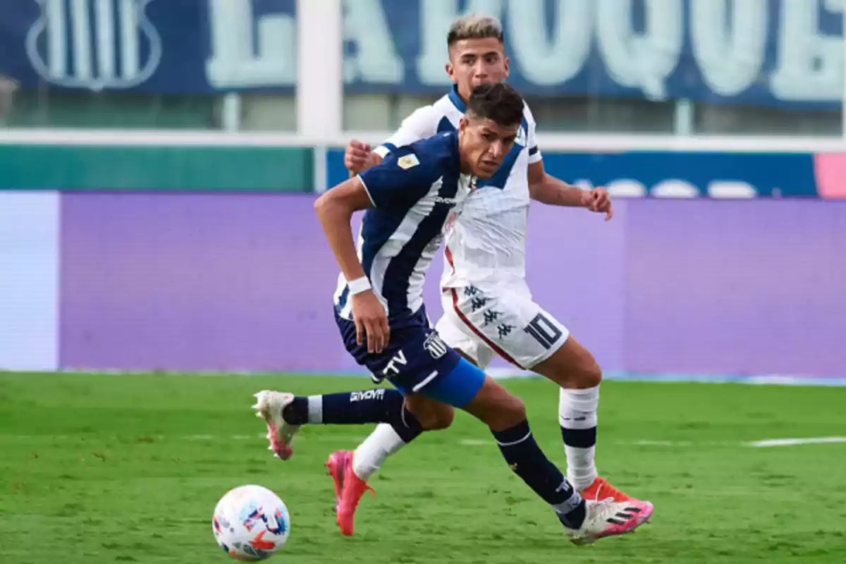 Dos futbolistas disputan el balón durante un partido en una cancha de fútbol