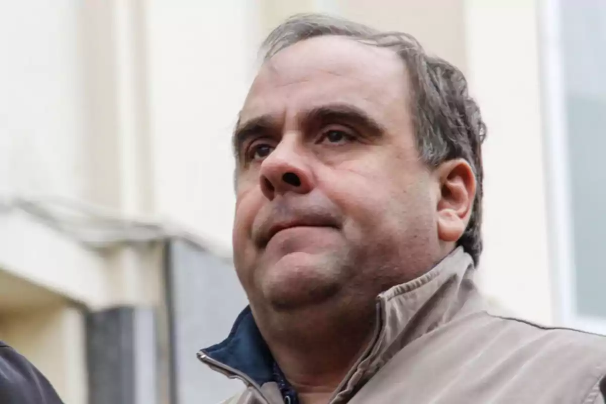 Hombre de mediana edad con chaqueta beige mirando hacia el frente en un entorno urbano Hombre de mediana edad con chaqueta beige mirando hacia el frente en un entorno urbano
