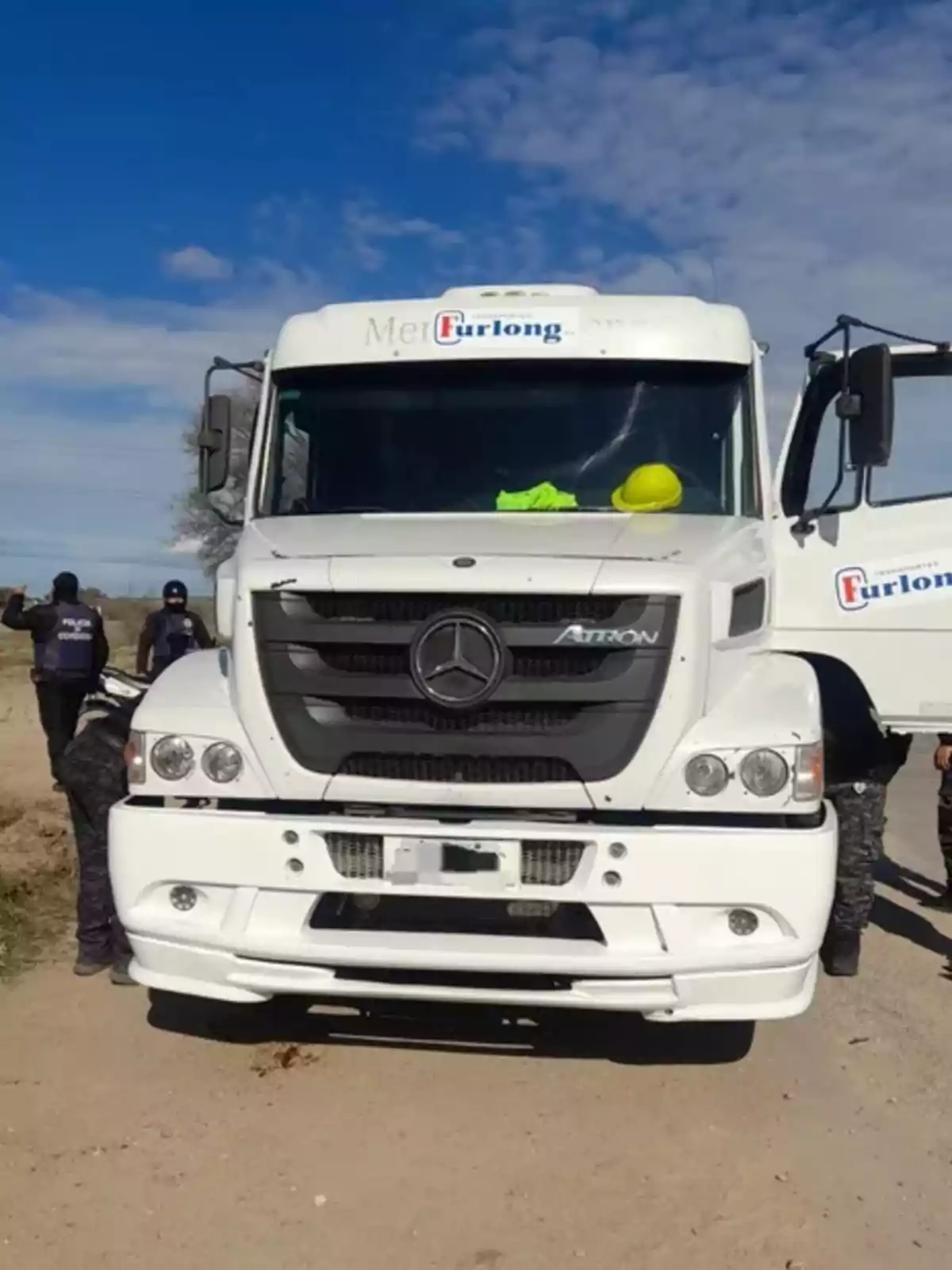 Camión blanco de la marca Mercedes-Benz detenido en un camino de tierra con varias personas uniformadas a su alrededor Camión blanco de la marca Mercedes-Benz detenido en un camino de tierra con varias personas uniformadas a su alrededor