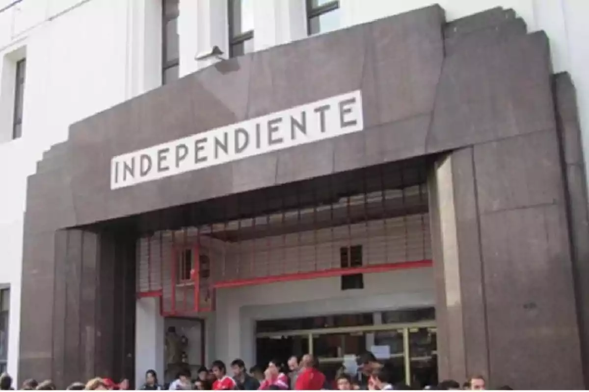 Main entrance of a building with the sign "Independiente" and several people gathered at the bottom