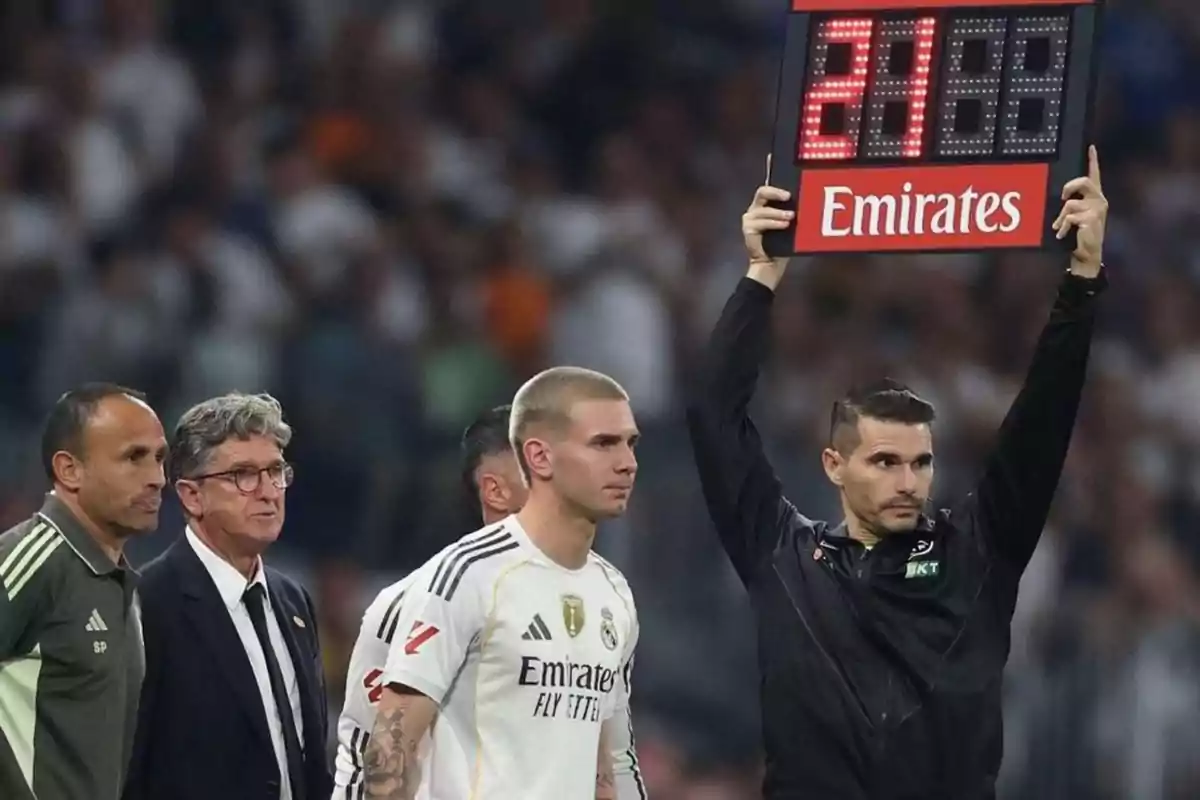A fourth official holds an electronic substitution board while a Real Madrid player gets ready to enter the field alongside members of the coaching staff. A fourth official holds an electronic substitution board while a Real Madrid player gets ready to enter the field alongside members of the coaching staff.