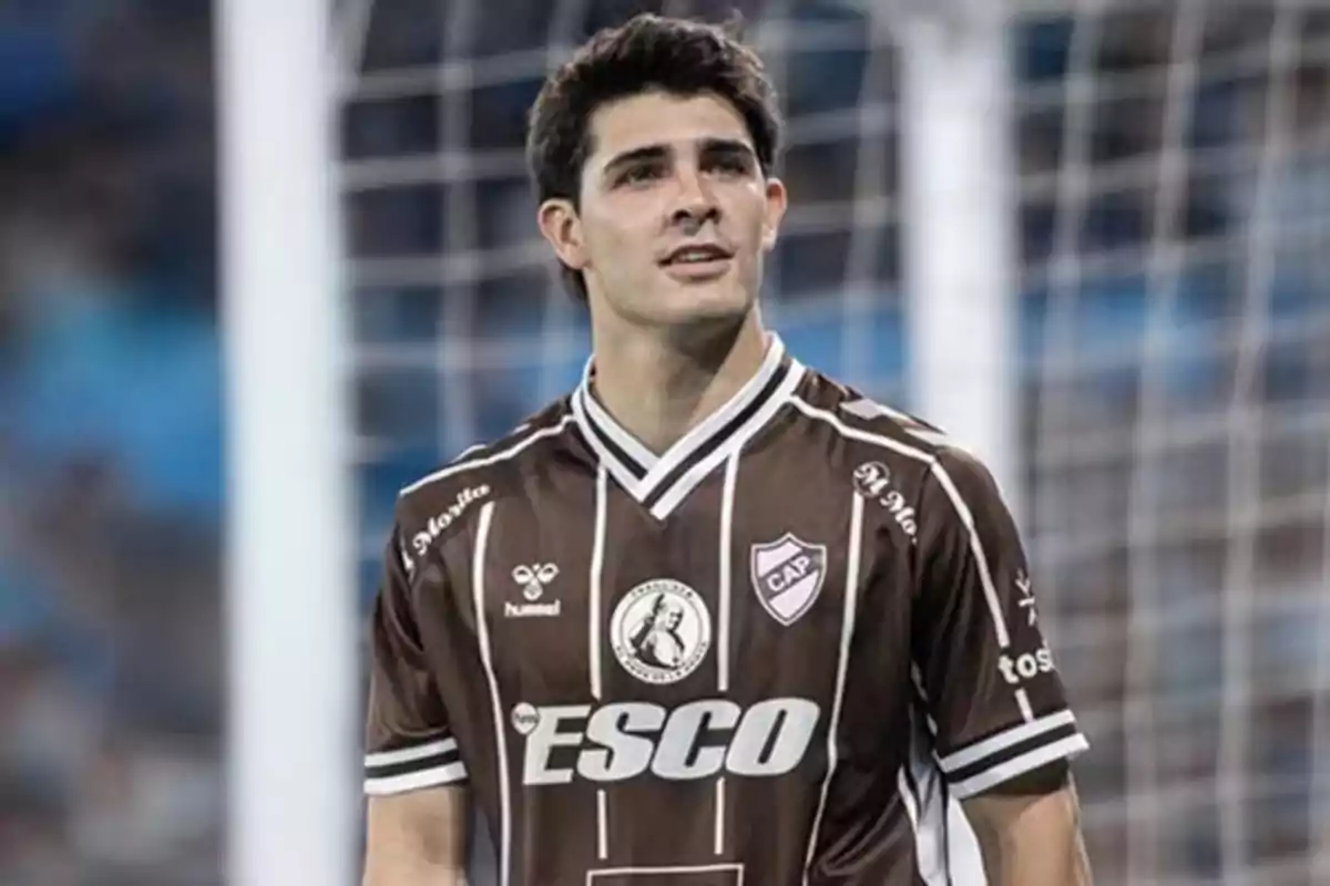 Jugador de fútbol con uniforme marrón y blanco de Club Atlético Platense en una cancha