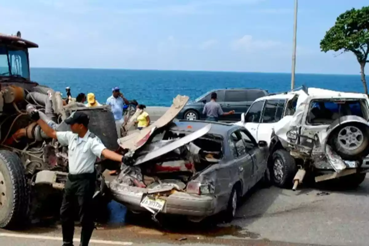 Accidente vial con varios vehículos dañados cerca del mar y un oficial dirigiendo el tráfico