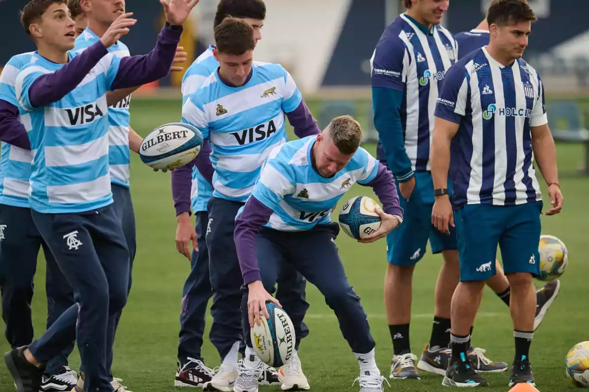 Jugadores de rugby entrenando en una cancha mientras sostienen balones y visten uniformes deportivos celestes y blancos Jugadores de rugby entrenando en una cancha mientras sostienen balones y visten uniformes deportivos celestes y blancos