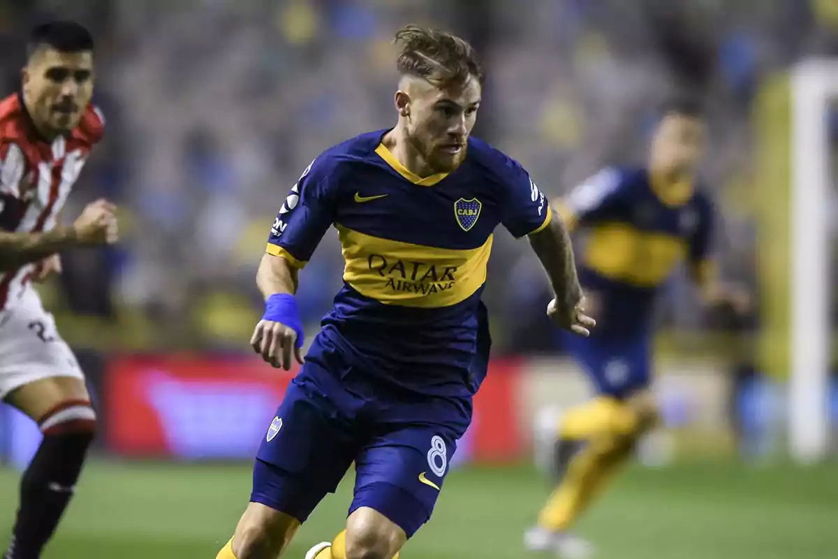 Boca Juniors player running with the ball during a match while an opposing player chases him
