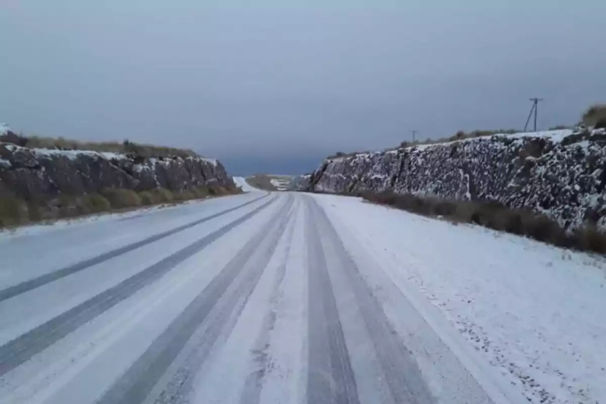 Carretera cubierta de nieve entre dos paredes de roca bajo un cielo nublado