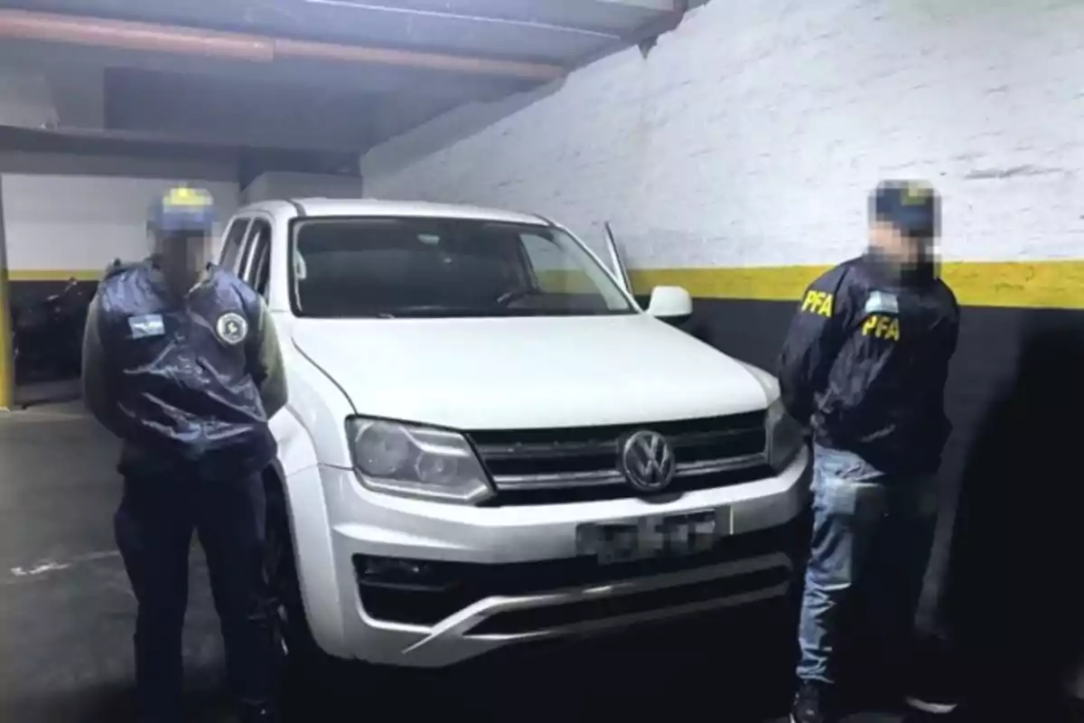 Dos personas con chalecos de la policía federal posan junto a una camioneta blanca Volkswagen en un estacionamiento subterráneo Dos personas con chalecos de la policía federal posan junto a una camioneta blanca Volkswagen en un estacionamiento subterráneo