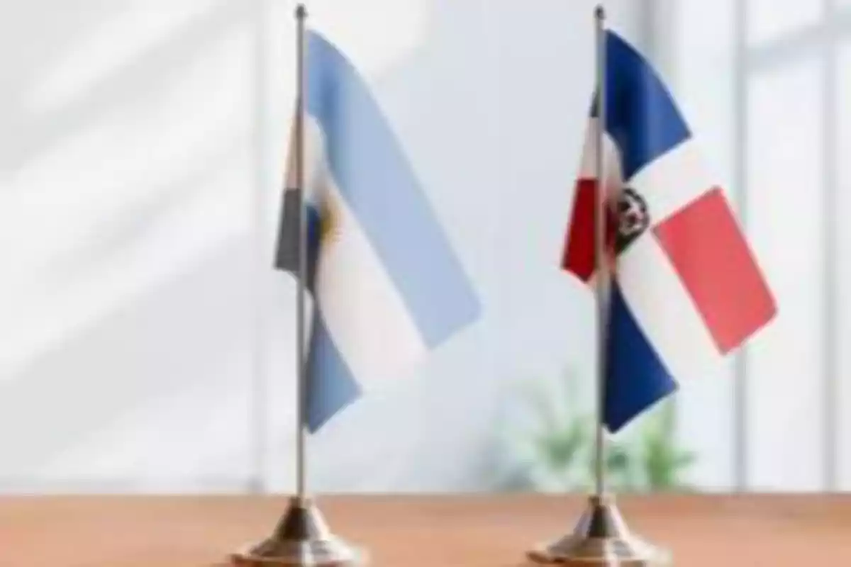 Dos banderas pequeñas de Argentina y República Dominicana sobre una mesa en un ambiente iluminado