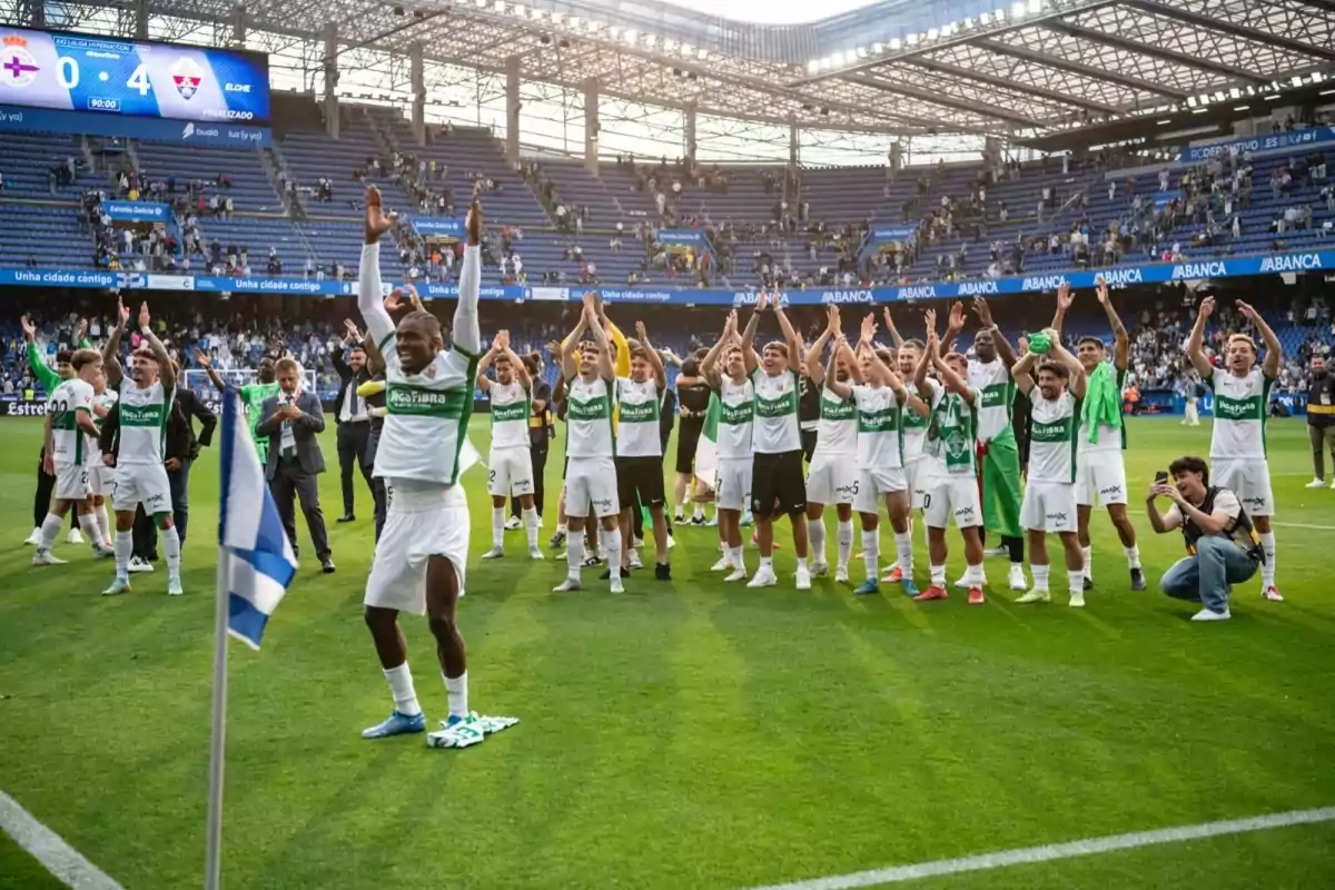 Soccer team players celebrate a victory on the field by raising their arms while a photographer captures the moment and the scoreboard shows a favorable result. Soccer team players celebrate a victory on the field by raising their arms while a photographer captures the moment and the scoreboard shows a favorable result.