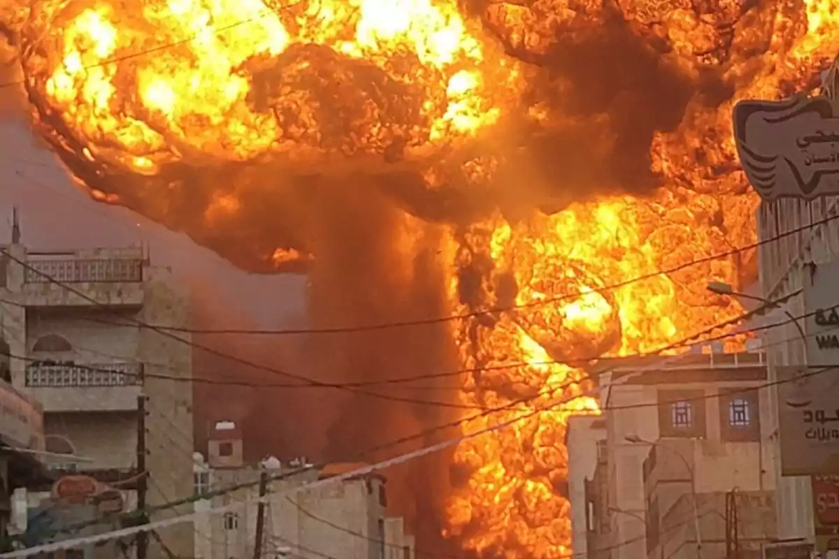 Massive explosion of fire and smoke in an urban area surrounded by buildings and power lines