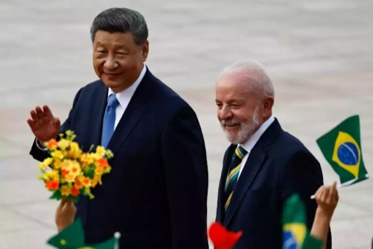 Dos hombres con traje caminan juntos mientras una persona les ofrece un ramo de flores y otras ondean banderas de Brasil