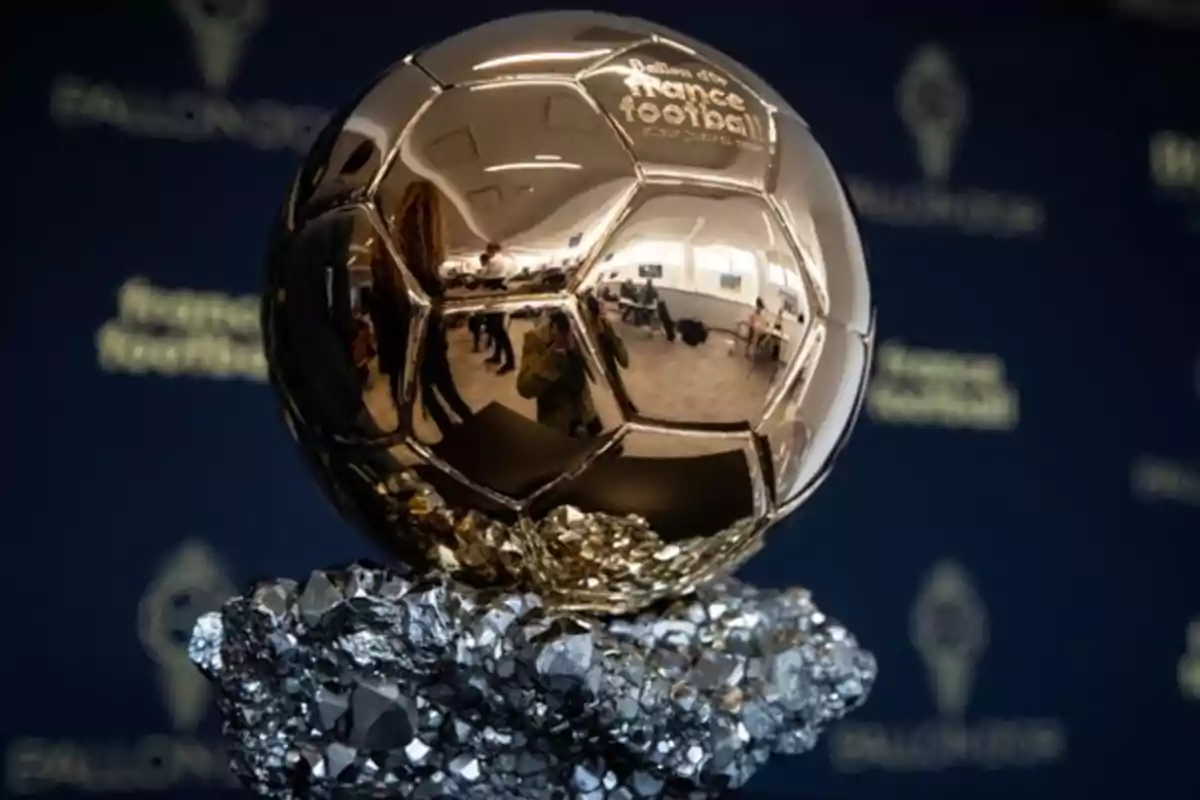 Golden Ballon d'Or trophy on a rocky base with a blurred blue background