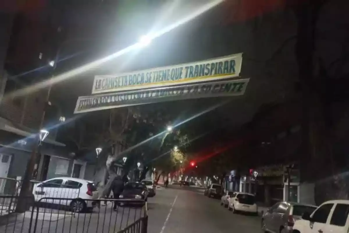 Street at night with parked cars and a hanging sign that says the Boca jersey has to be sweated. Street at night with parked cars and a hanging sign that says the Boca jersey has to be sweated.