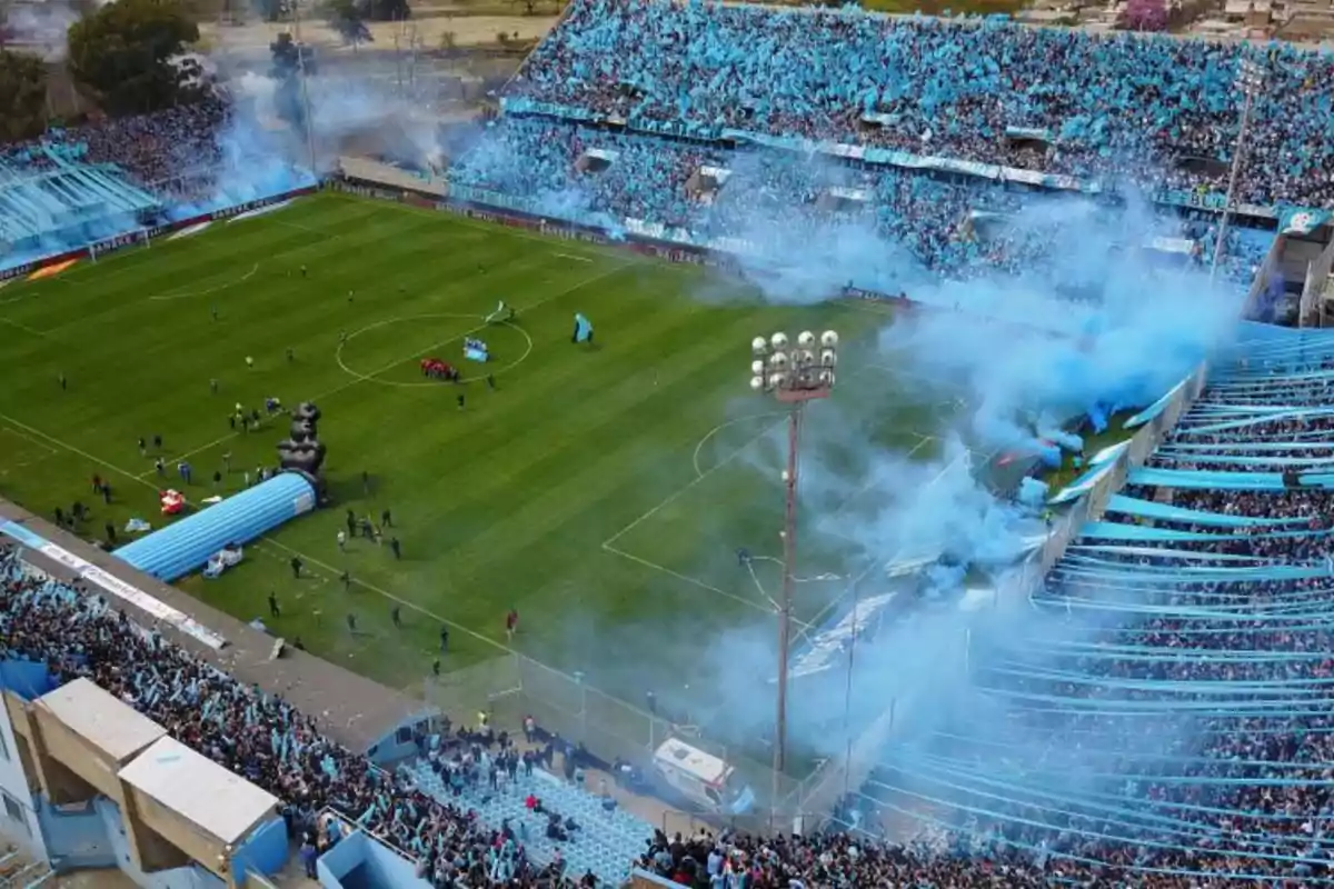 Soccer stadium full of fans with blue smoke and flags celebrating before a match