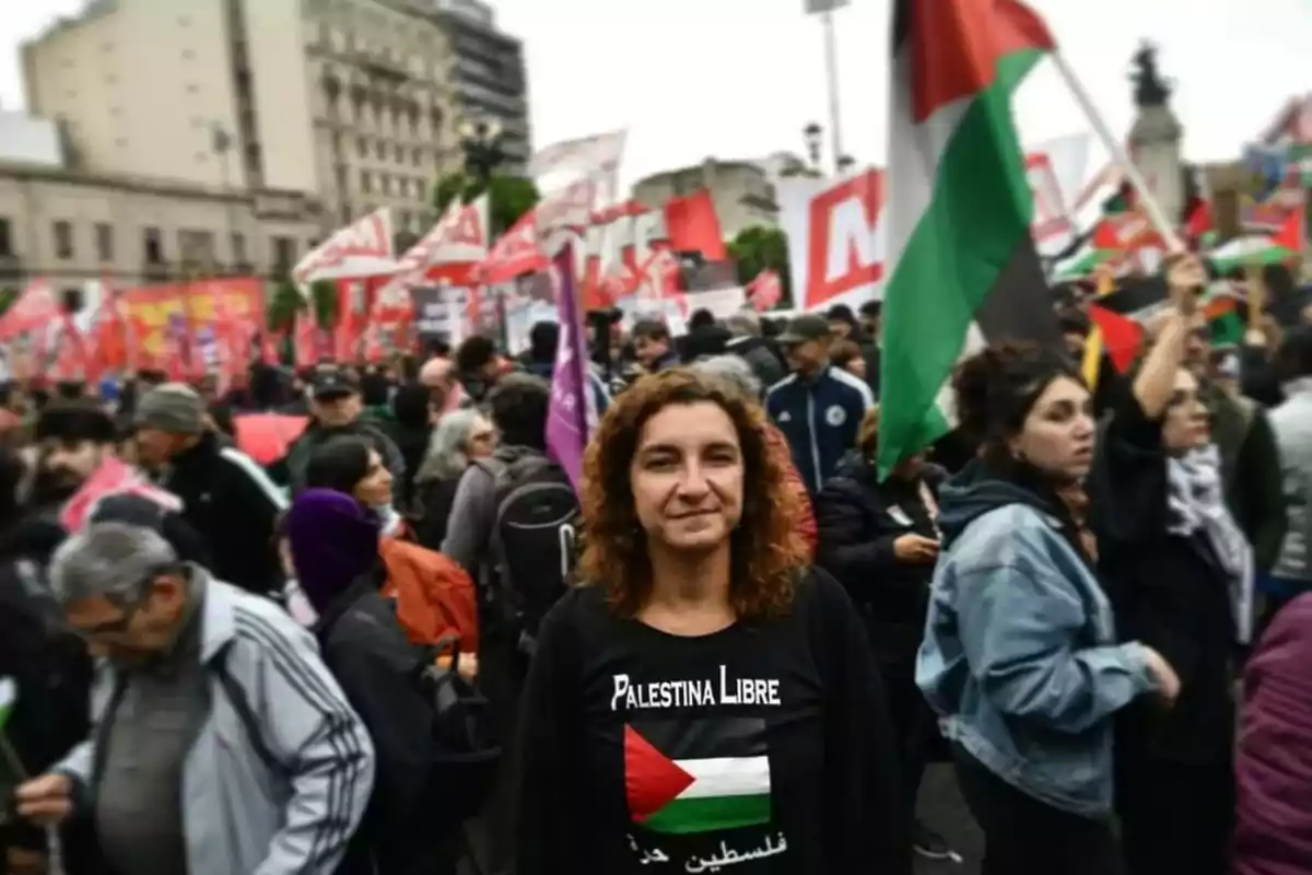 Woman wearing a jersey that says Free Palestine at a demonstration with many people and flags in the background Woman wearing a jersey that says Free Palestine at a demonstration with many people and flags in the background