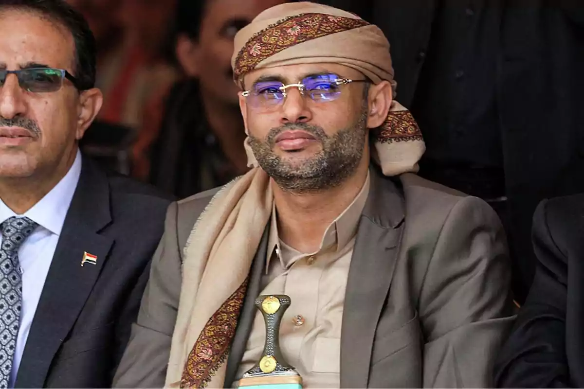 Man with glasses and traditional turban seated at a formal event Man with glasses and traditional turban seated at a formal event