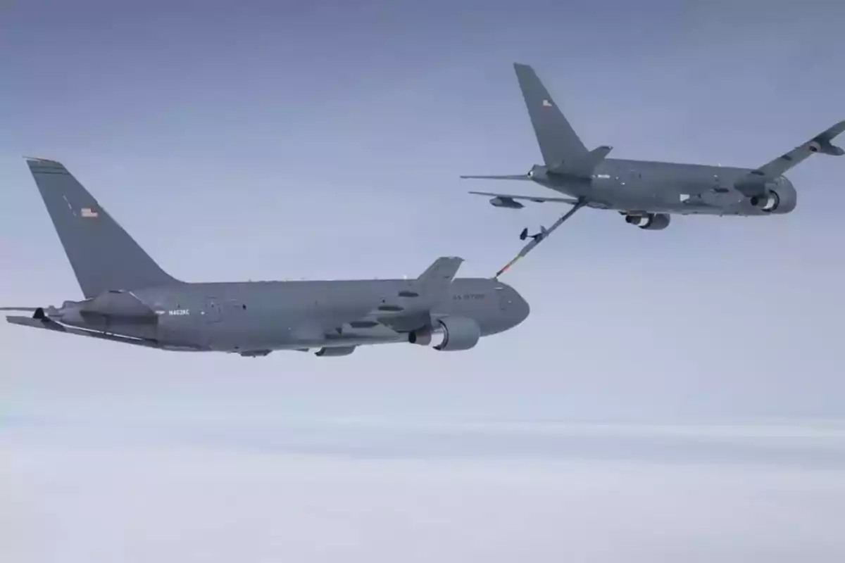 Dos aviones militares en pleno proceso de reabastecimiento de combustible en el aire sobre un fondo de nubes y cielo gris. Dos aviones militares en pleno proceso de reabastecimiento de combustible en el aire sobre un fondo de nubes y cielo gris.