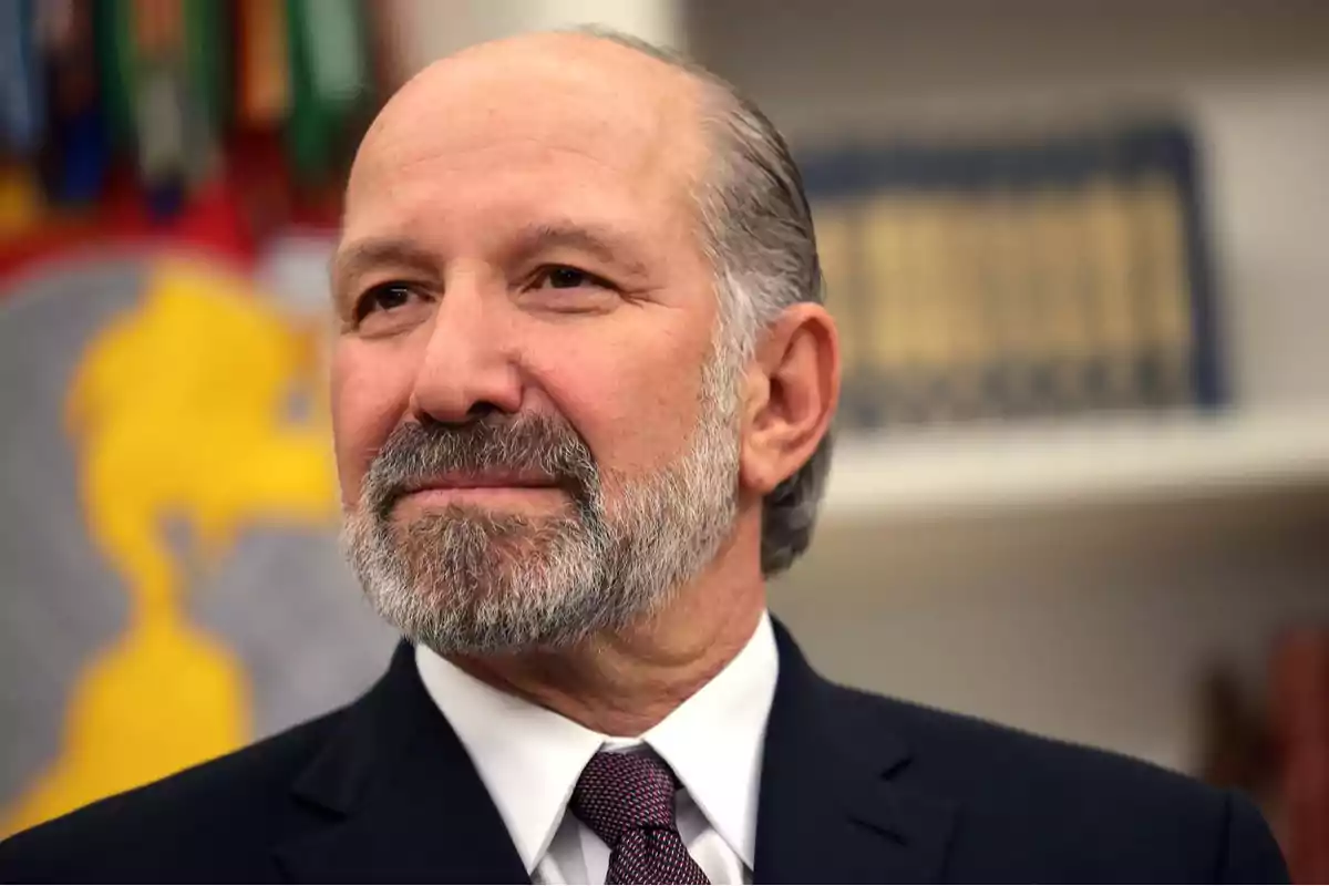 Middle-aged man with gray beard and mustache wearing a dark suit and tie, looking to the side with a serious expression, blurred background with books and a map. Middle-aged man with gray beard and mustache wearing a dark suit and tie, looking to the side with a serious expression, blurred background with books and a map.