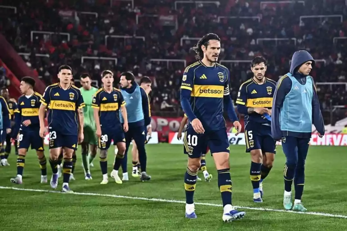 Boca Juniors players walking on the soccer field with serious expressions after a match Boca Juniors players walking on the soccer field with serious expressions after a match