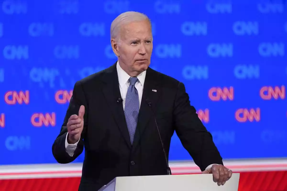 Gray-haired man in a dark suit and blue tie speaking at a podium in front of a blue background with CNN logos Gray-haired man in a dark suit and blue tie speaking at a podium in front of a blue background with CNN logos