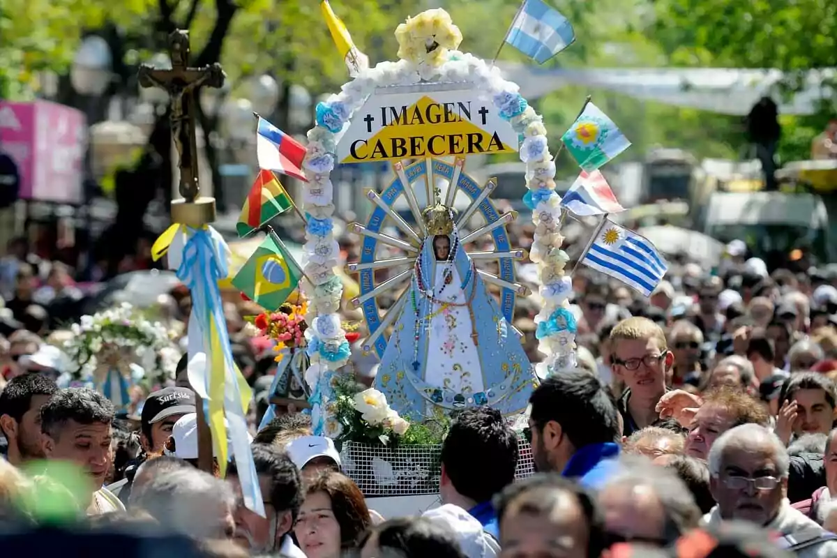 Religious procession with a crowd of people accompanying an image of the Virgin decorated with flowers and flags from various countries Religious procession with a crowd of people accompanying an image of the Virgin decorated with flowers and flags from various countries