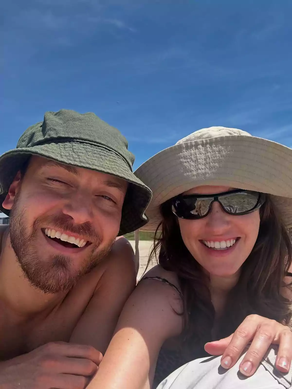 Smiling couple wearing wide-brimmed hats enjoying a sunny day at the beach Smiling couple wearing wide-brimmed hats enjoying a sunny day at the beach