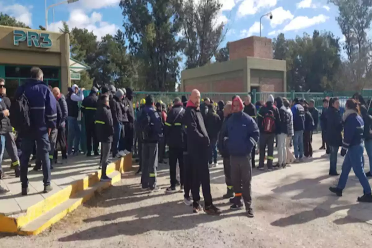 Un grupo de personas reunidas frente a un edificio con el cartel PR3 en un día soleado Un grupo de personas reunidas frente a un edificio con el cartel PR3 en un día soleado