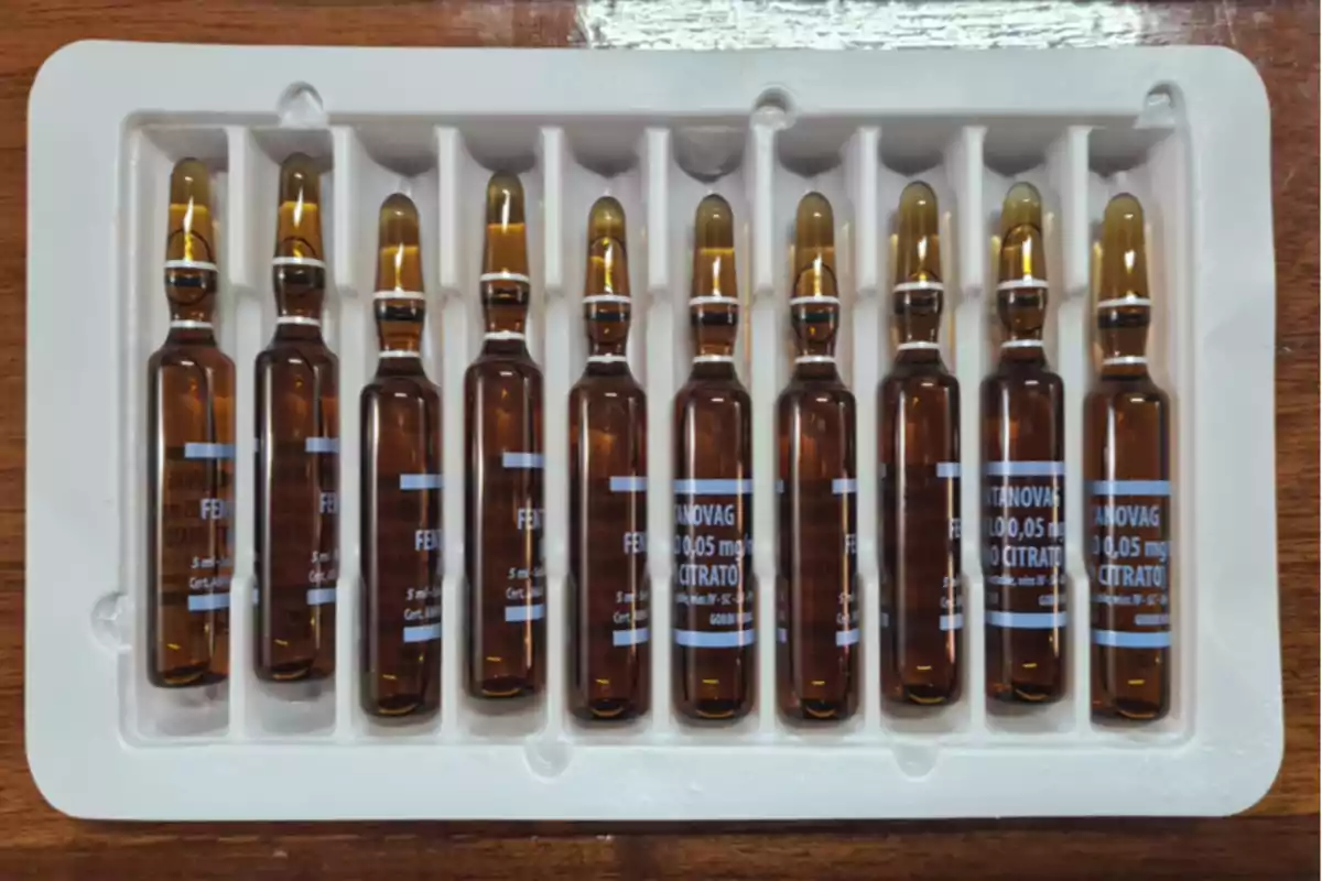 Diez ampolletas de vidrio color ámbar organizadas en una charola plástica blanca sobre una superficie de madera Diez ampolletas de vidrio color ámbar organizadas en una charola plástica blanca sobre una superficie de madera