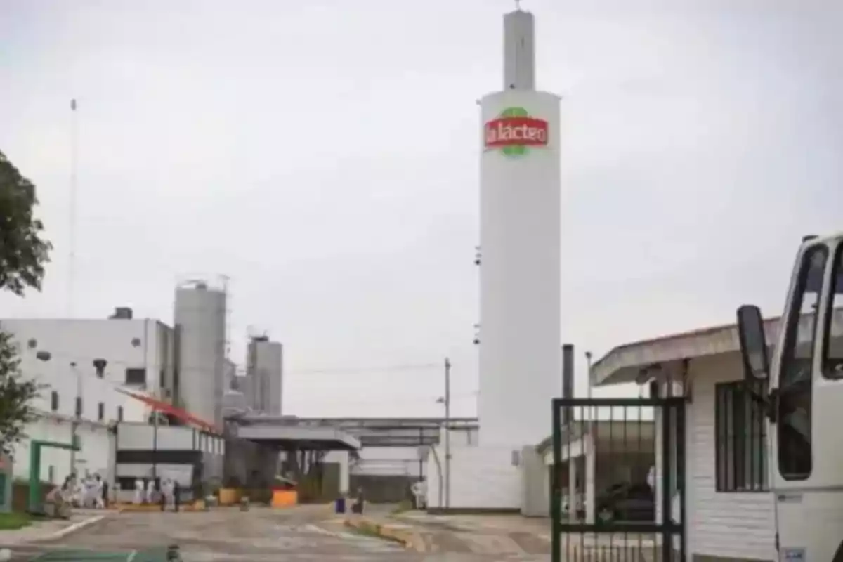 Vista exterior de una planta industrial de productos lácteos con un tanque blanco alto que tiene el logo de la empresa La Lácteo