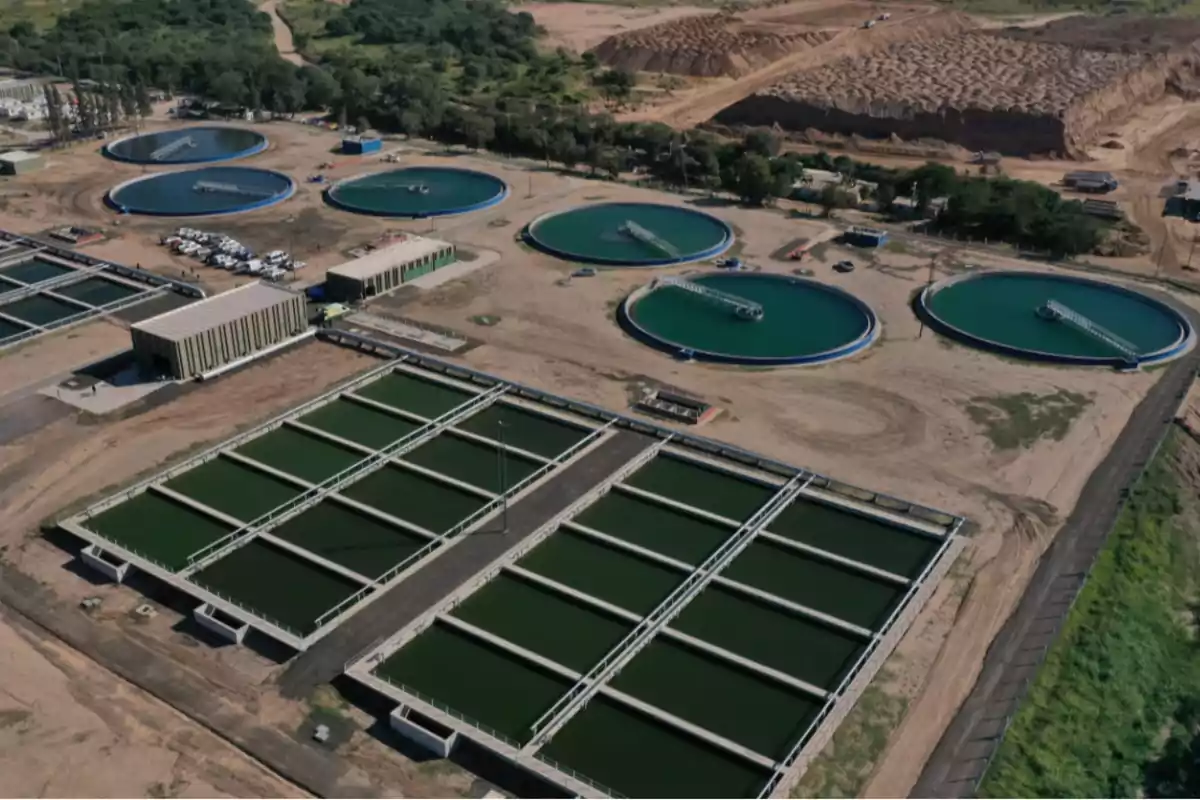 Vista aérea de una planta de tratamiento de aguas rodeada de áreas verdes y caminos de tierra Vista aérea de una planta de tratamiento de aguas rodeada de áreas verdes y caminos de tierra