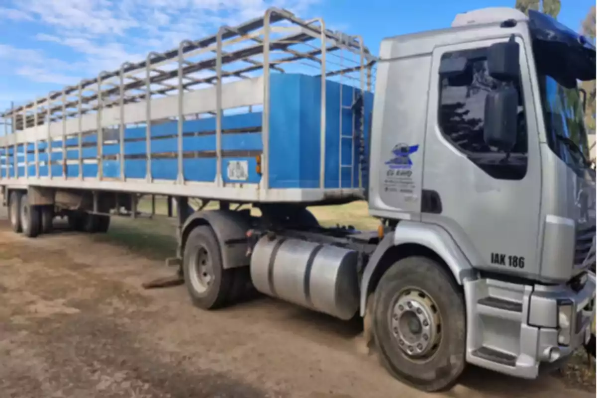 Silver cargo truck with a blue trailer parked on a dirt road Silver cargo truck with a blue trailer parked on a dirt road