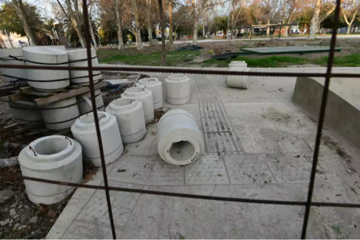Varios bloques cilíndricos de concreto apilados y distribuidos en una zona de construcción al aire libre rodeada de árboles Varios bloques cilíndricos de concreto apilados y distribuidos en una zona de construcción al aire libre rodeada de árboles