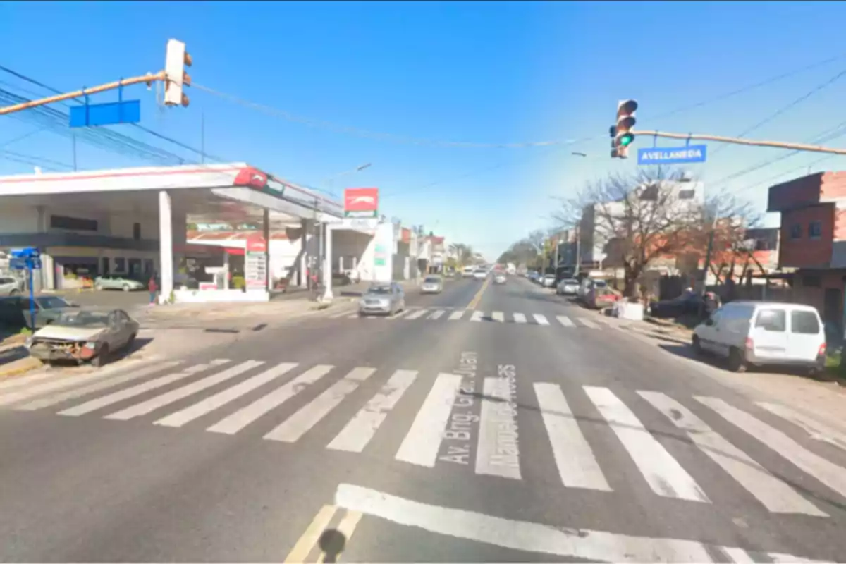 Intersection of avenues with a green traffic light, gas station on the left, and several cars driving and parked Intersection of avenues with a green traffic light, gas station on the left, and several cars driving and parked